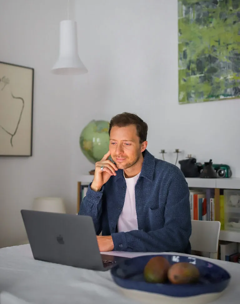 Simon Karim sitzt nachdenklich am Schreibtisch vor seinem Laptop