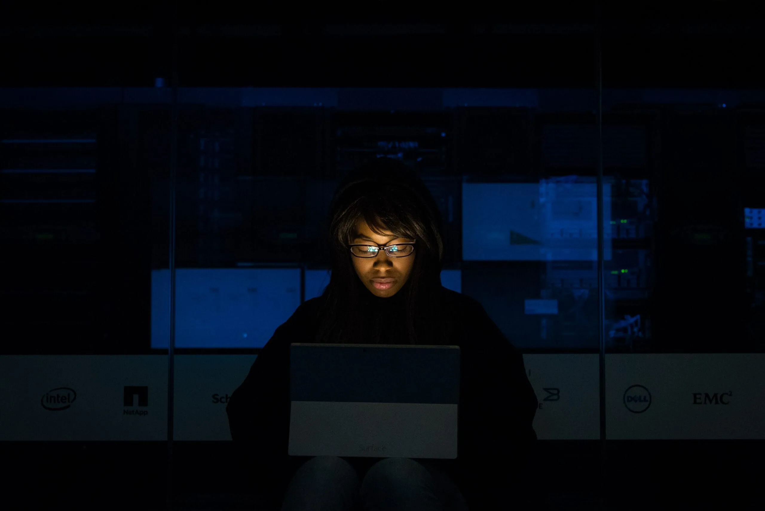Eine Person sitzt im dunklen Büro, ihr Gesicht wird nur vom Licht des Laptops beleuchtet