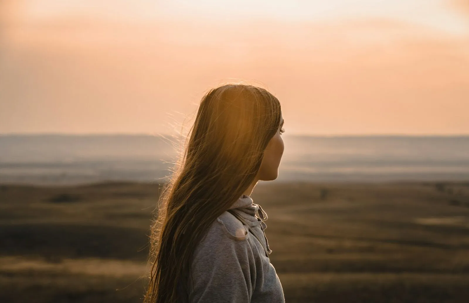 Eine Frau blickt im Abendlicht ruhig über eine weite Landschaft