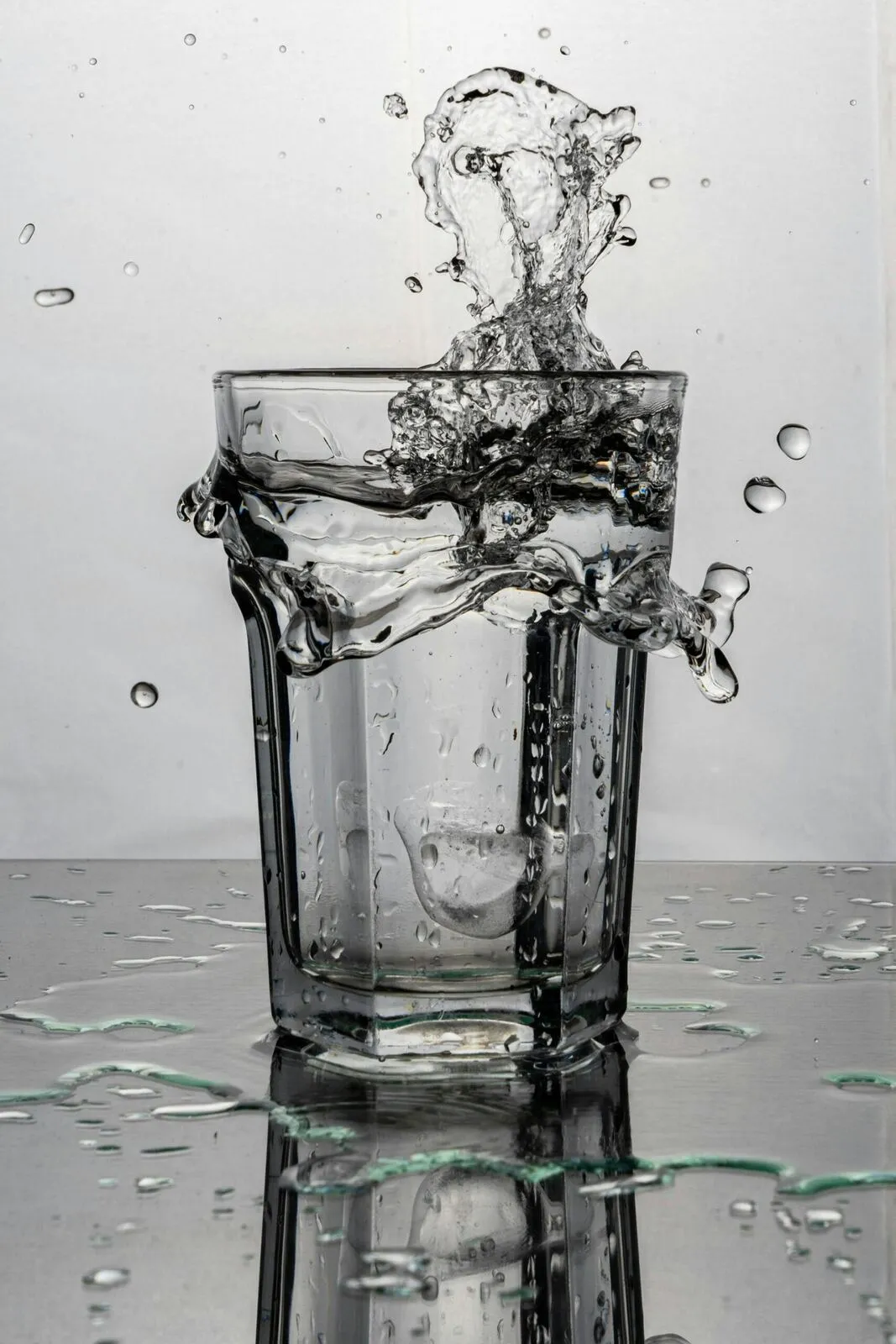 Wasser spritzt in einem Glas auf und gerät sichtbar in Bewegung