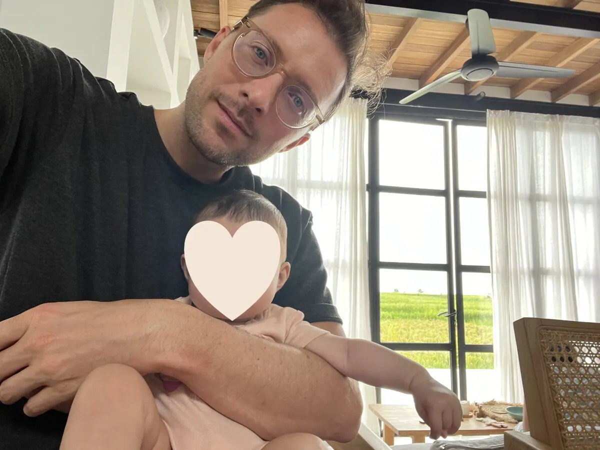 Simon Karim mit seinem Baby auf dem Arm in einem hellen Raum