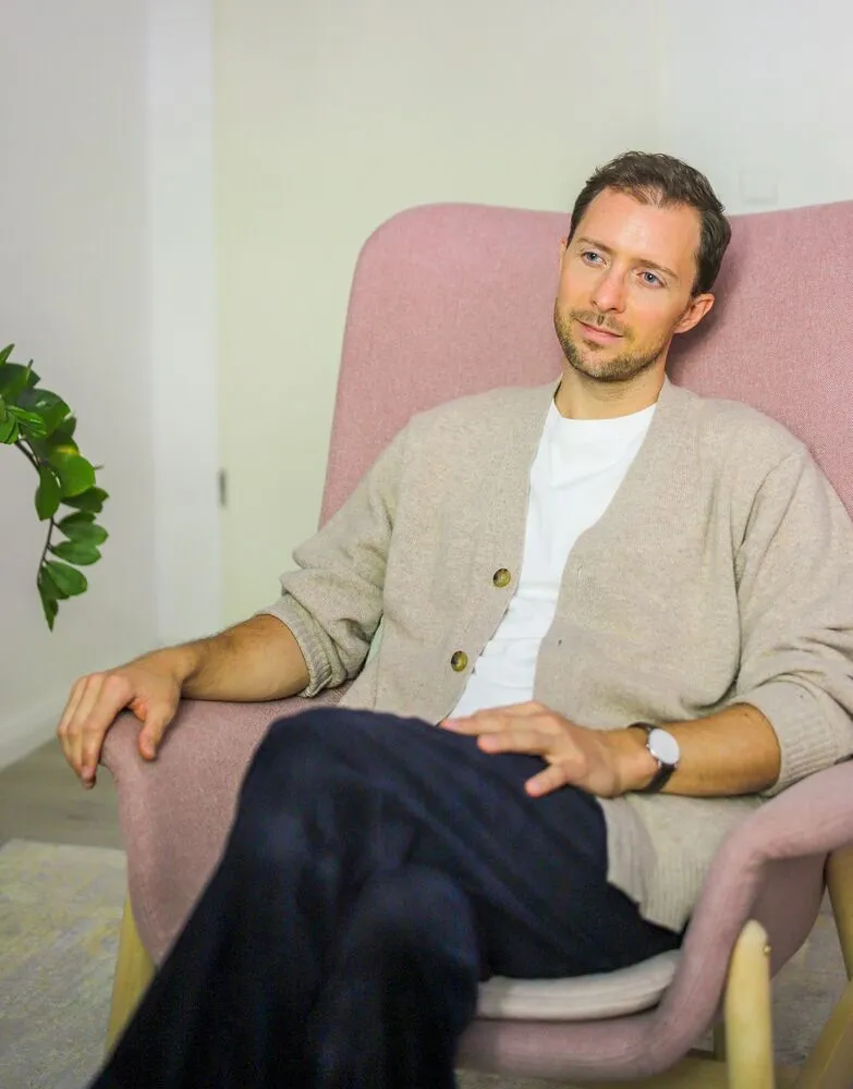Simon Karim sitzt entspannt in einem rosa Sessel